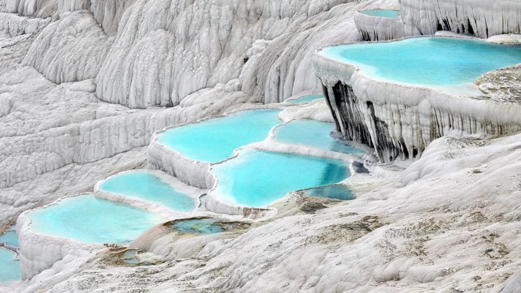 Terraced thermal pools at Pamukkale, Turkey, with vibrant turquoise water cascading down white travertine formations.
