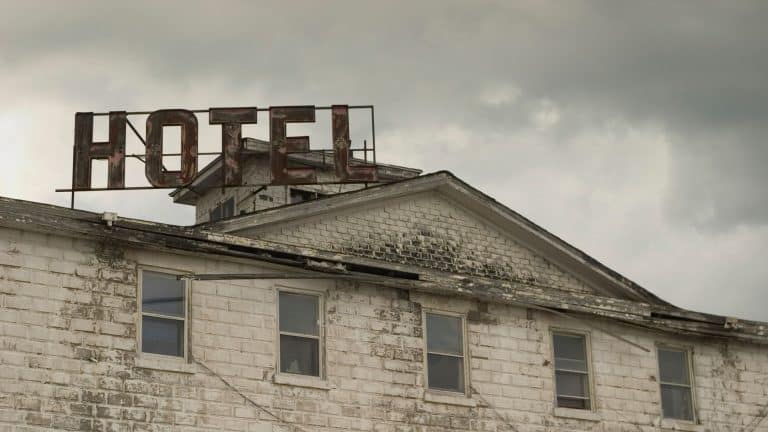 A run down weathered building with a faded red Hotel sign above the windows.