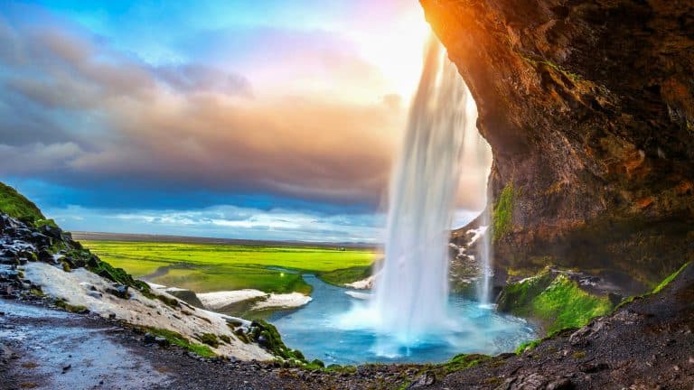 A beautiful waterfall in Iceland at sunset with a beautiful backdrop behind the falls