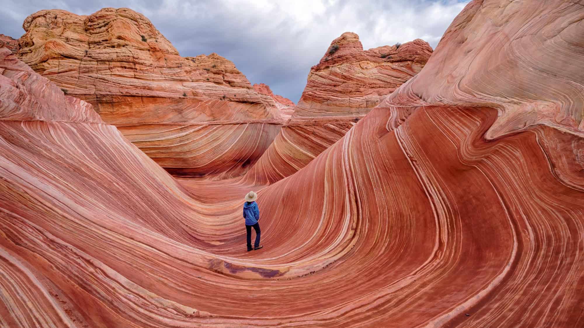 A hiker stands in the midst of the rock formation known as the wave in Arizona/Utah.