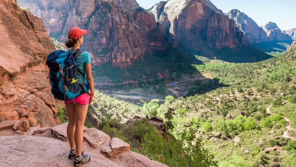 A female hiker stands at a lookout on the Angel's Landing trail in Zion National Park.
