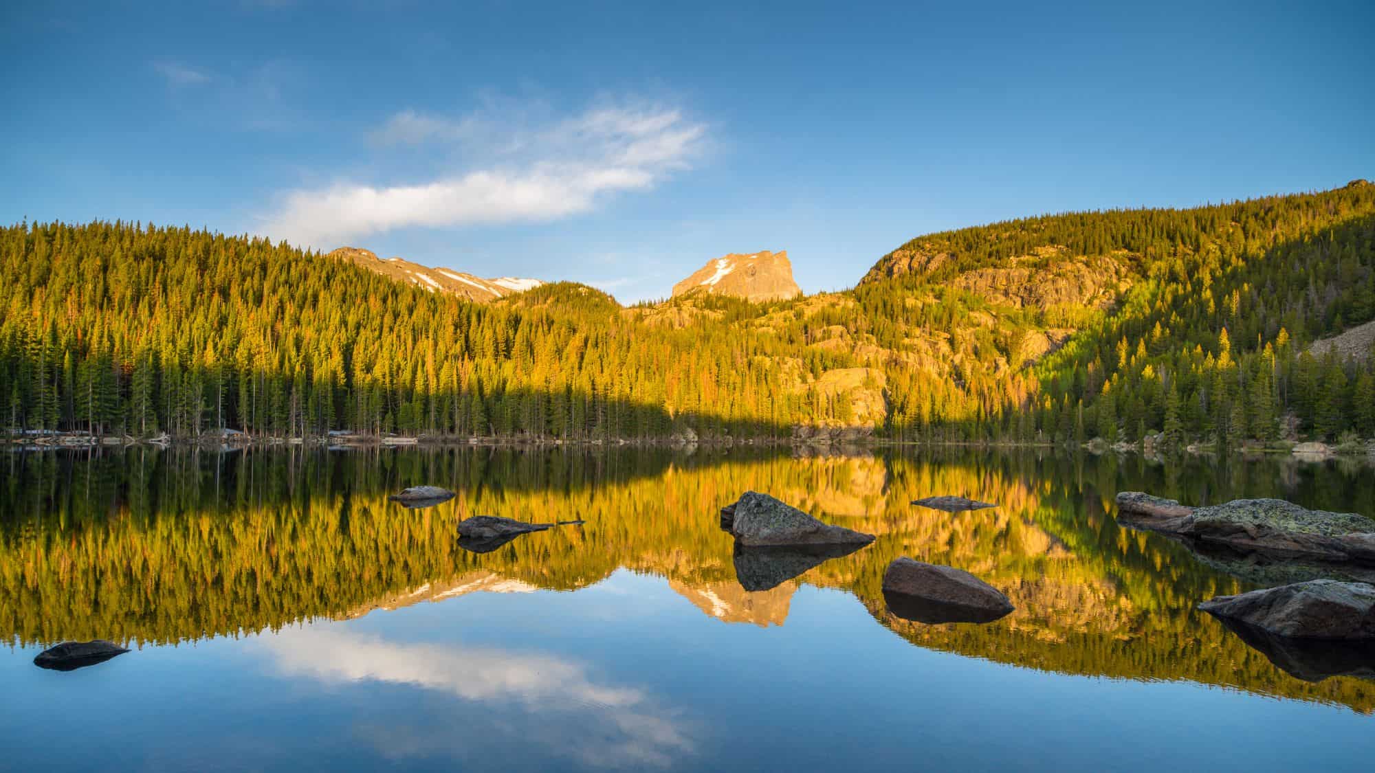 Sunset at Bear Lake with rocks jutting out of the calm lake as well as a reflection of the surrounding tree lines.