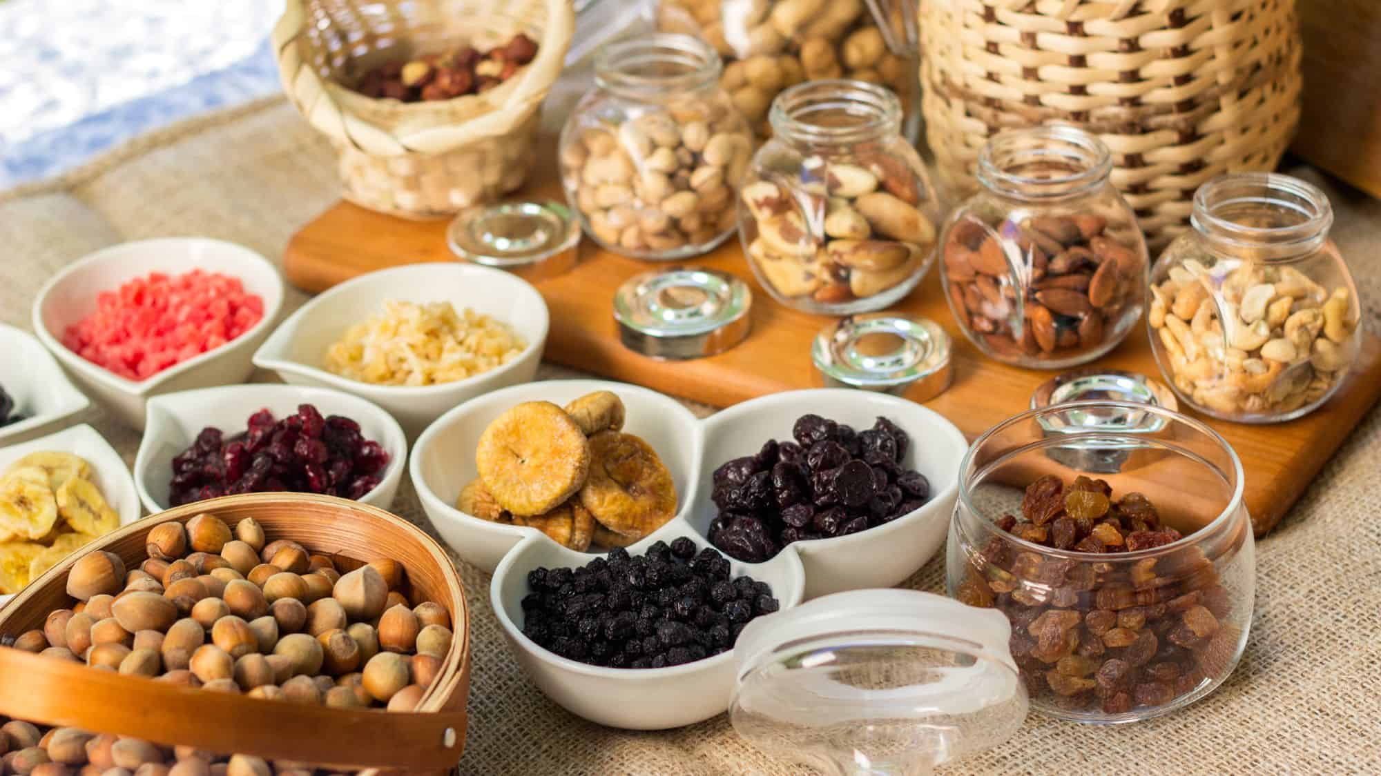 An assortment of dried fruits, nuts, and seeds beautifully displayed in bowls and jars, ideal for creating custom trail mix combinations.