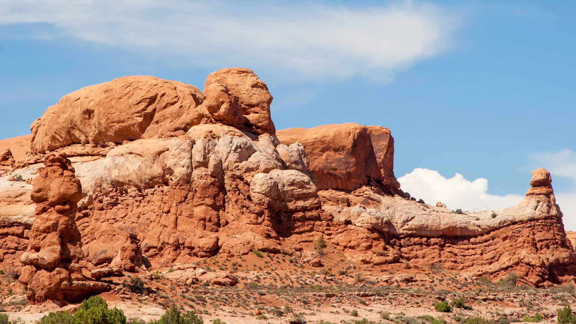 A striking red sandstone formation against a bright blue sky in Arches National Park, highlighting the park's unique and colorful desert landscape.