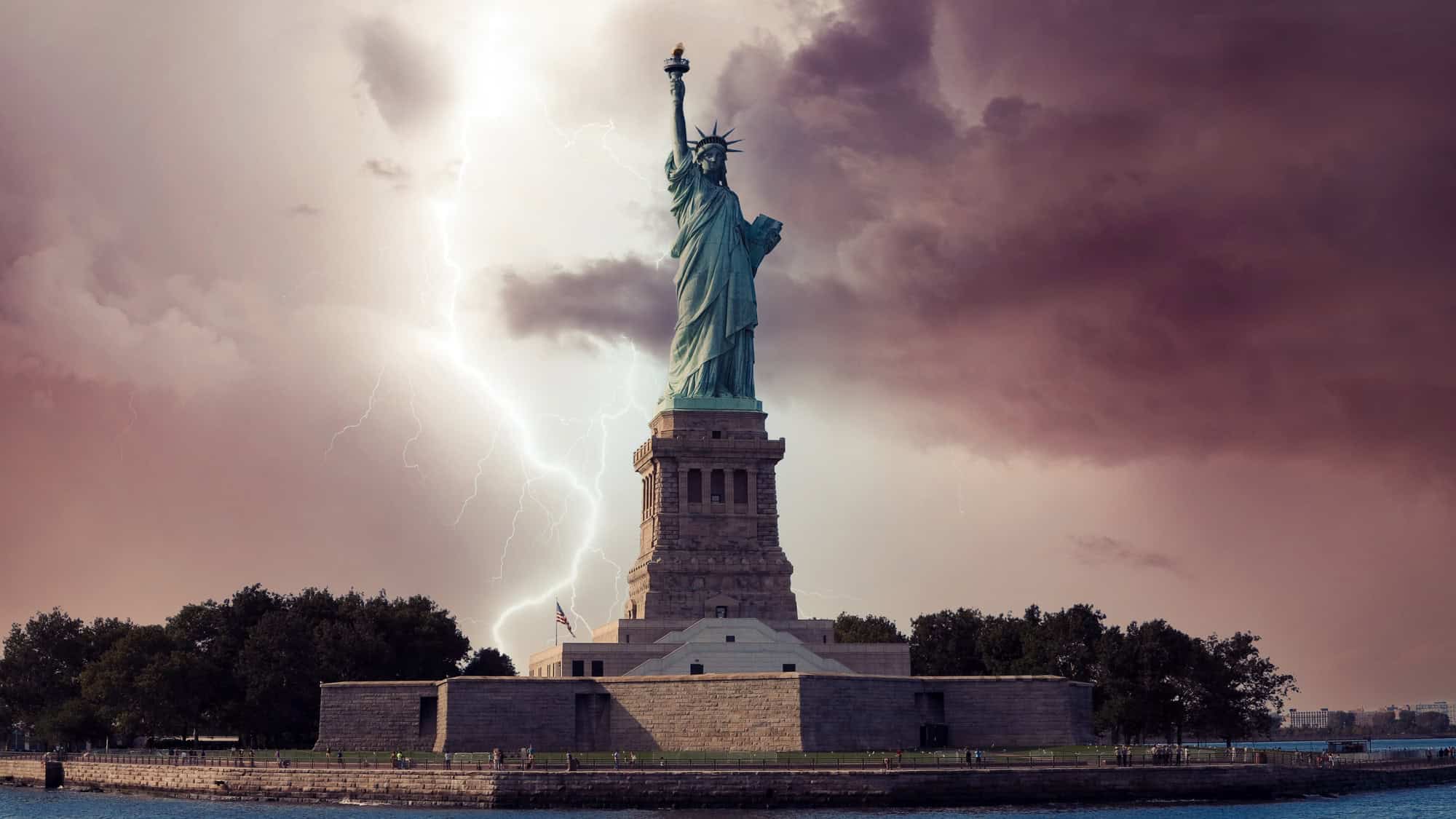 The Statue of Liberty stands tall against a dramatic stormy sky, illuminated by bright lightning bolts, symbolizing resilience amidst turbulent weather.