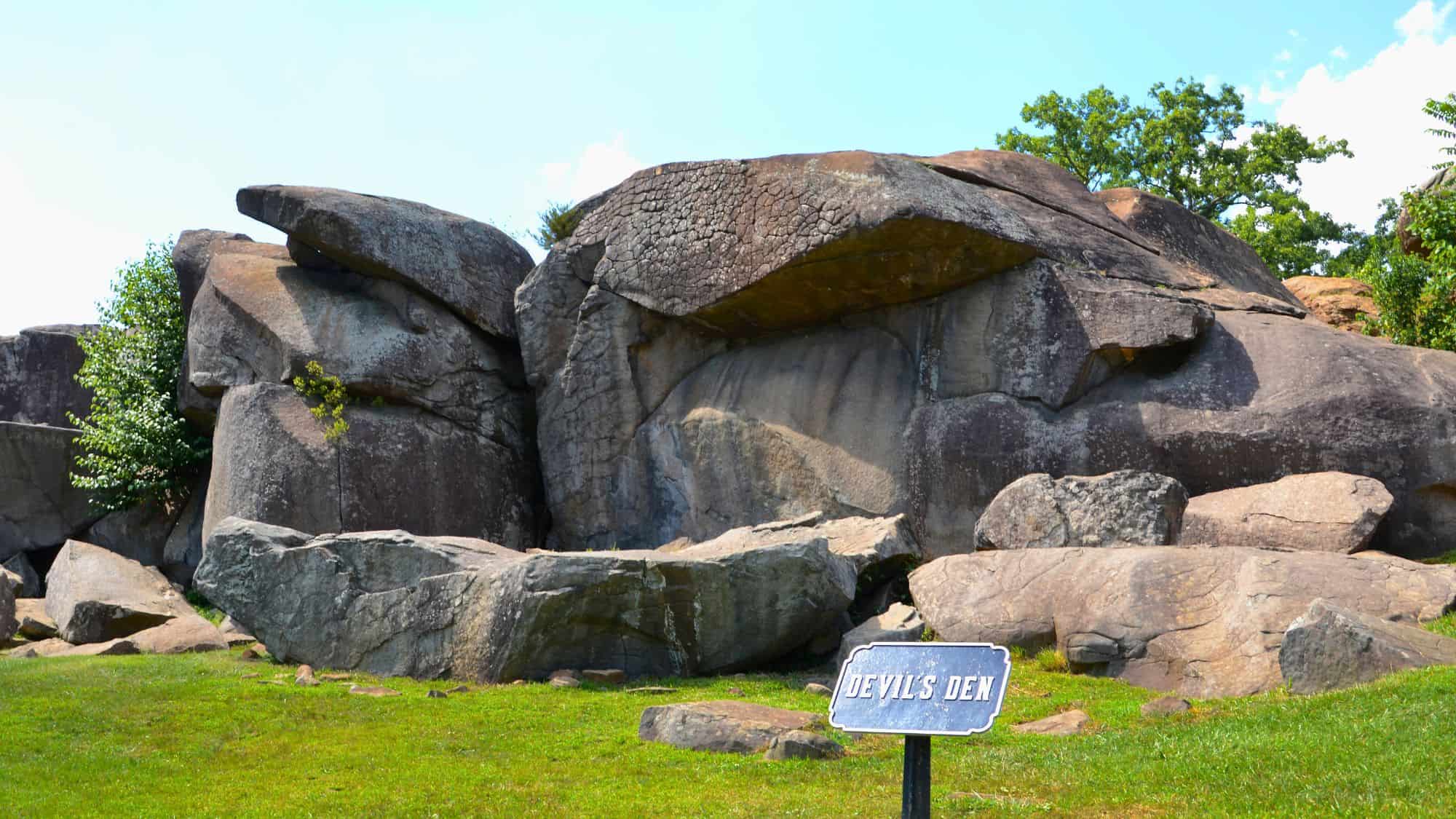Massive boulders form the dramatic and rugged landscape of Devil’s Den in Gettysburg, Pennsylvania, with a small sign in front marking the site's name.