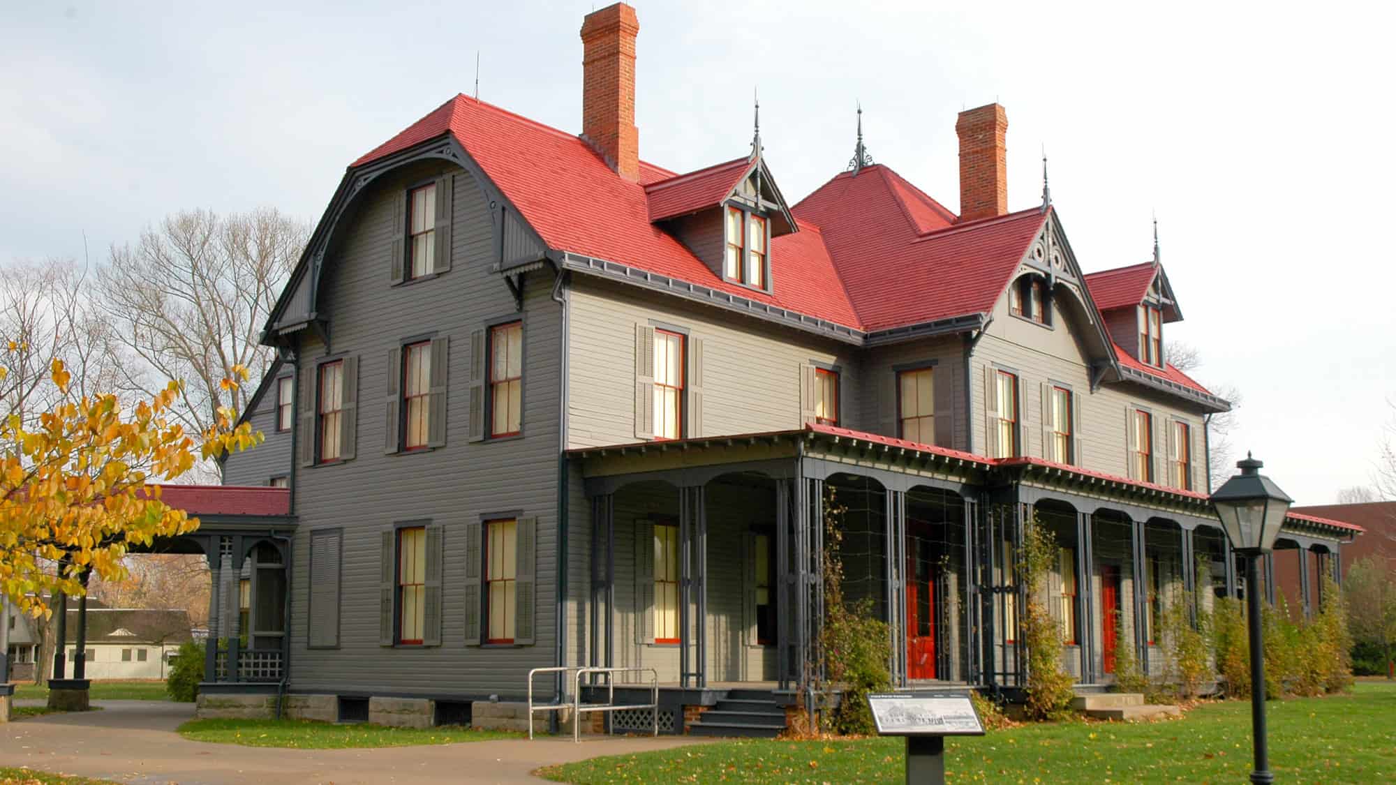 A large, elegant 19th-century house painted in gray with a red roof and dark trim, framed by leafless trees and fall foliage. This is the preserved home of President James A. Garfield.