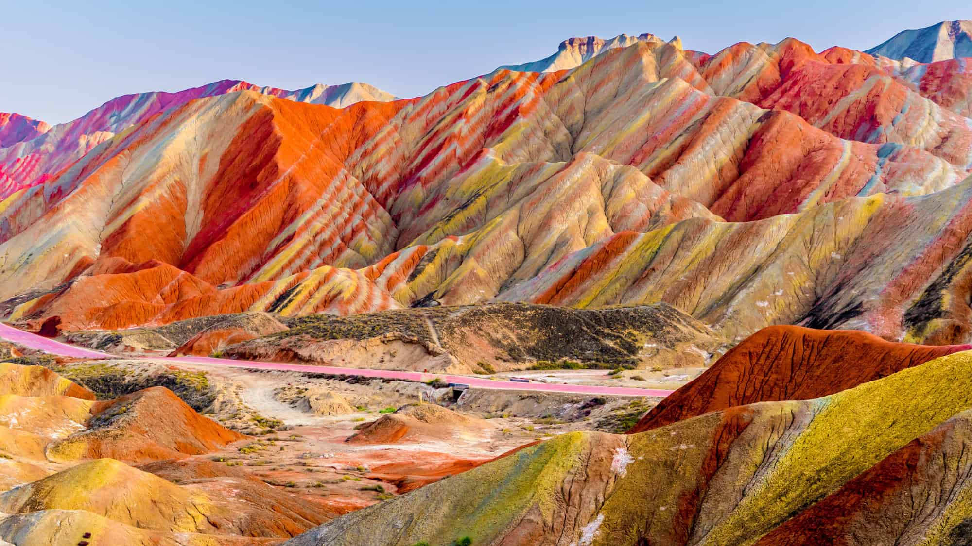 The Zhangye Danxia Landform in China displays vividly striped hills in red, orange, yellow, and lavender, looking like a painted masterpiece formed by layers of sandstone and minerals.