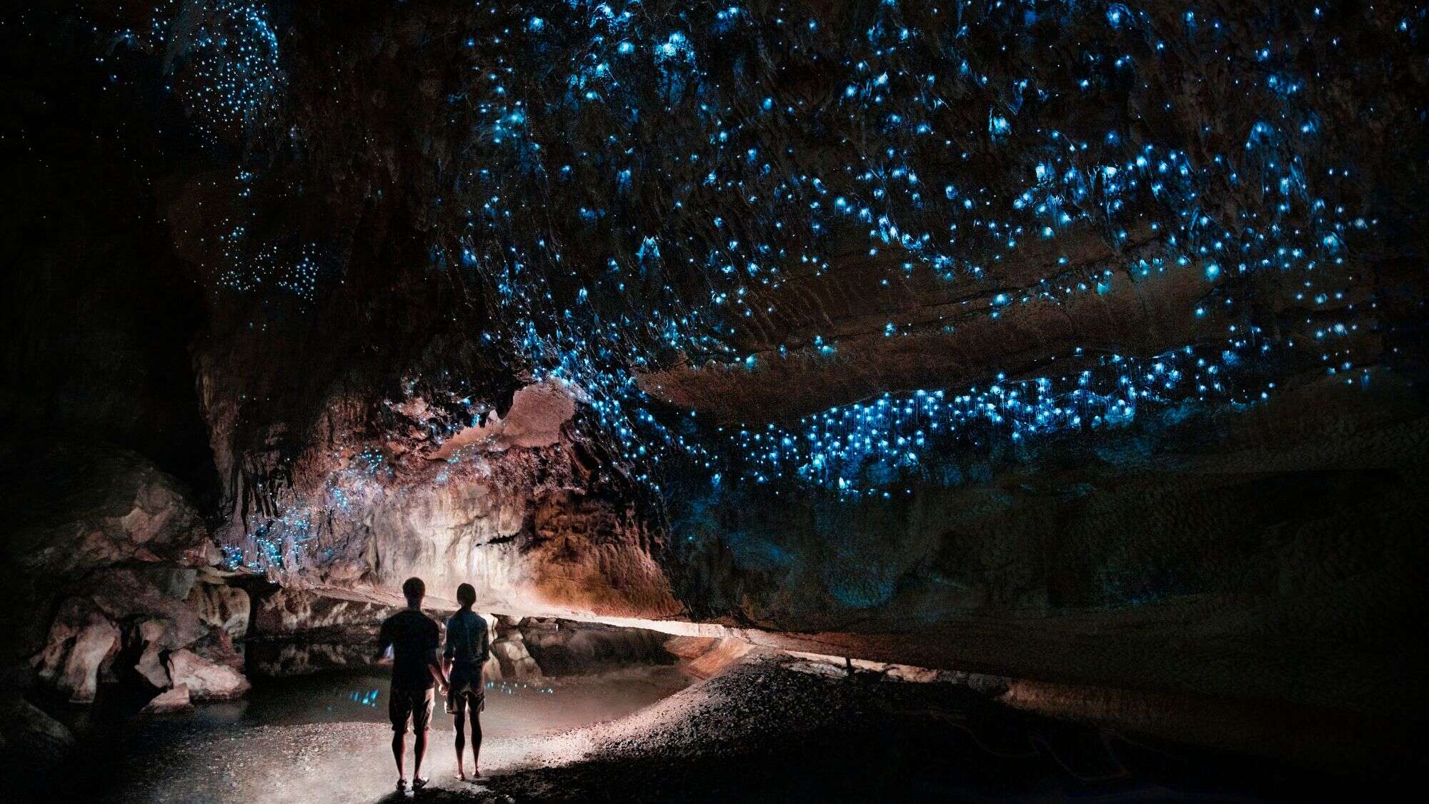 A couple stands on a path in the Waipu glowworm cave in New Zealand.
