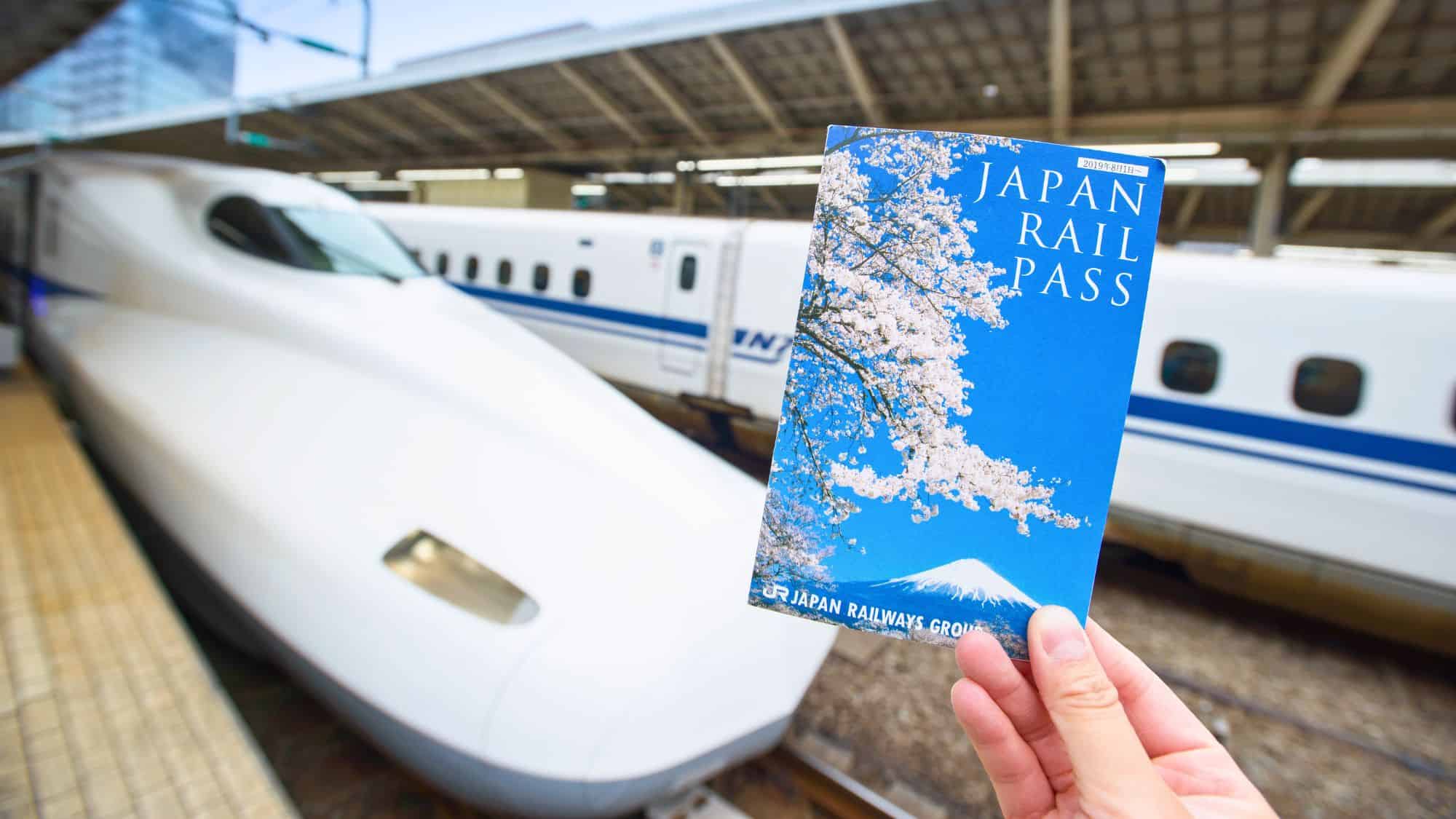 Tokyo, Japan - Dec 11, 2019: Japan Rail Pass Image, hand hold JR Pass ticket in front of Shinkansen at Tokyo Station. JR Pass is a rail pass coupon for overseas visitors unlimited bullet train ride.