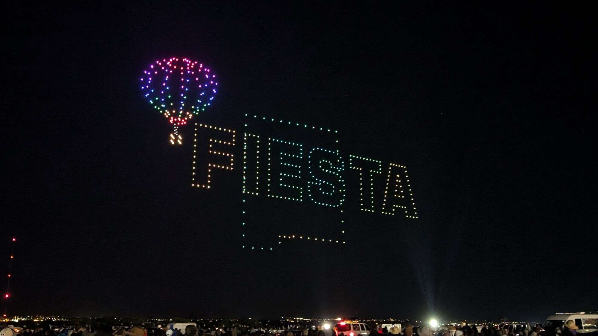 A night sky display spells out “Fiesta” with a rainbow balloon image, created by hundreds of glowing drones.