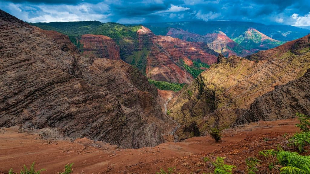 Jagged ridges and deep valleys reveal layers of red and green rock in Hawaii’s Grand Canyon of the Pacific.