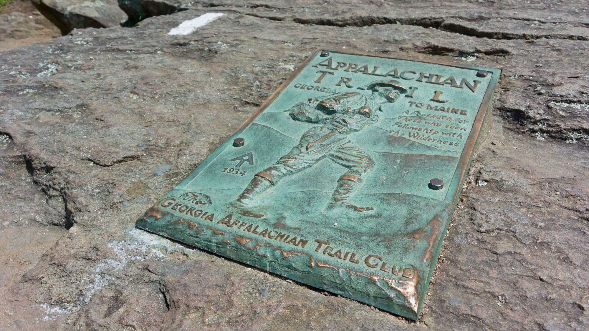 A bronze plaque embedded in rock marks the start of the Appalachian Trail in Georgia, honoring hikers and the enduring legacy of this iconic trail.