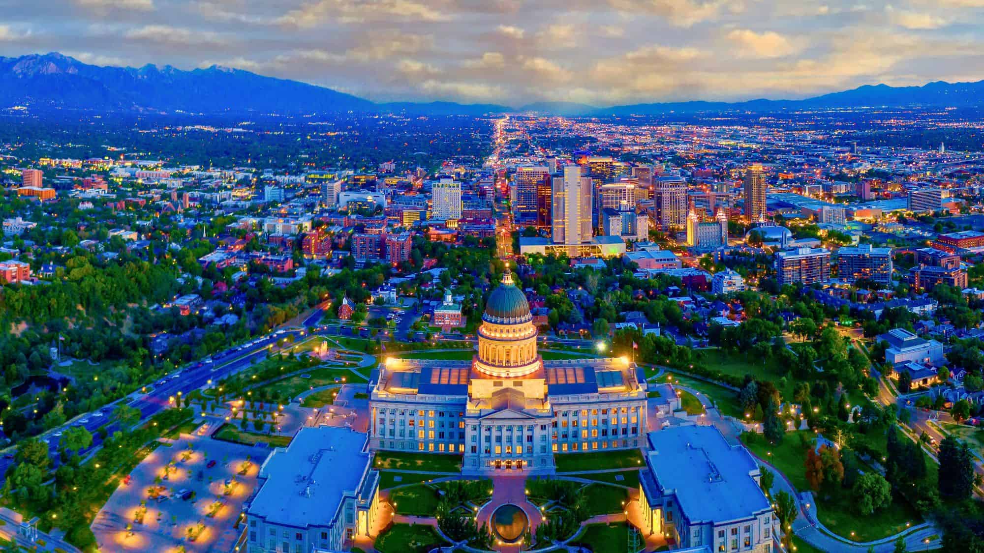 The Utah State Capitol anchors this striking aerial image of Salt Lake City, where wide avenues and urban buildings stretch out toward the Wasatch Mountains.
