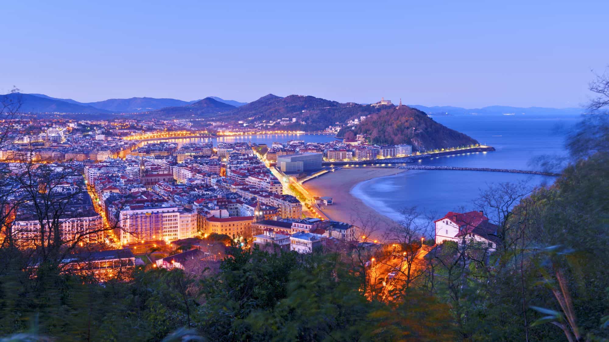 Golden lights trace the curve of La Concha Bay in San Sebastián, Spain, with hills, beach, and sea coming together in a scenic coastal embrace.