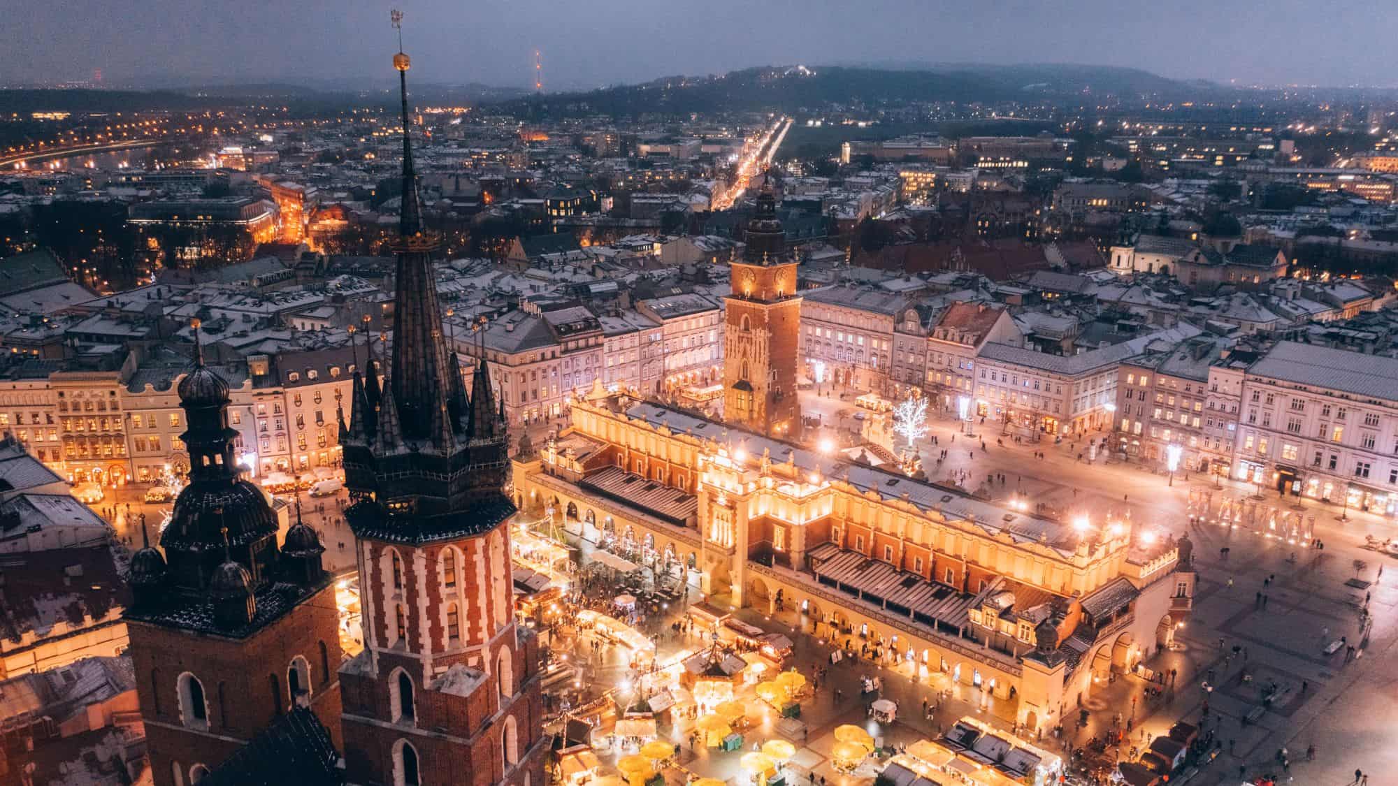 Kraków’s main square glows with golden lights, the Cloth Hall and St. Mary's Basilica standing out as festive stalls fill the plaza.