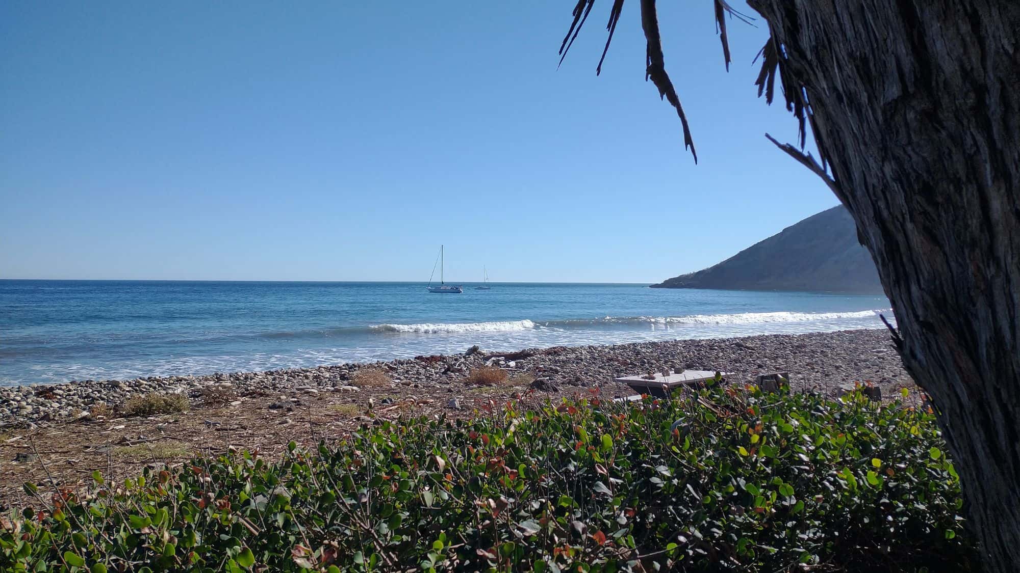 The coast of the channel islands with a few boats out in the water.